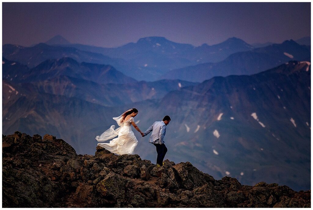 A bride and a groom on the top of Uncompaghre peak in Southern Colorado at sunrise for their hiking elopement