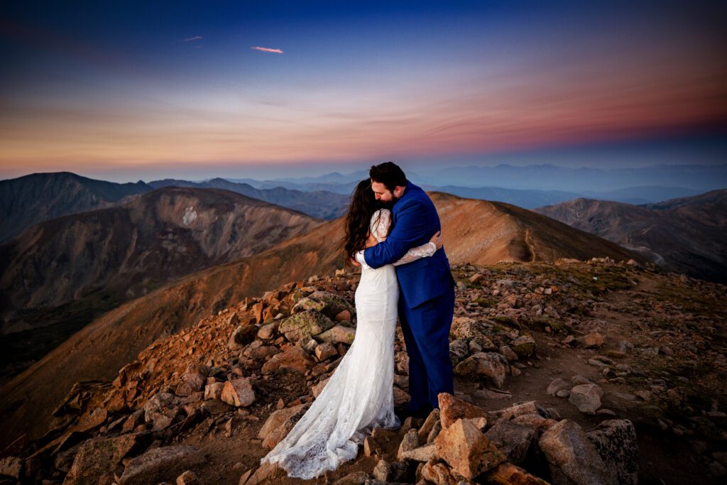 A bride and groom embrace after saying their vows on Mt. Sniktau at sunrise 