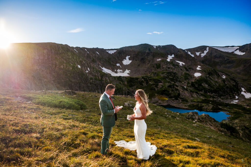 A bride and a groom saying their vows to one another above King Lake in the indian peaks wilderness 