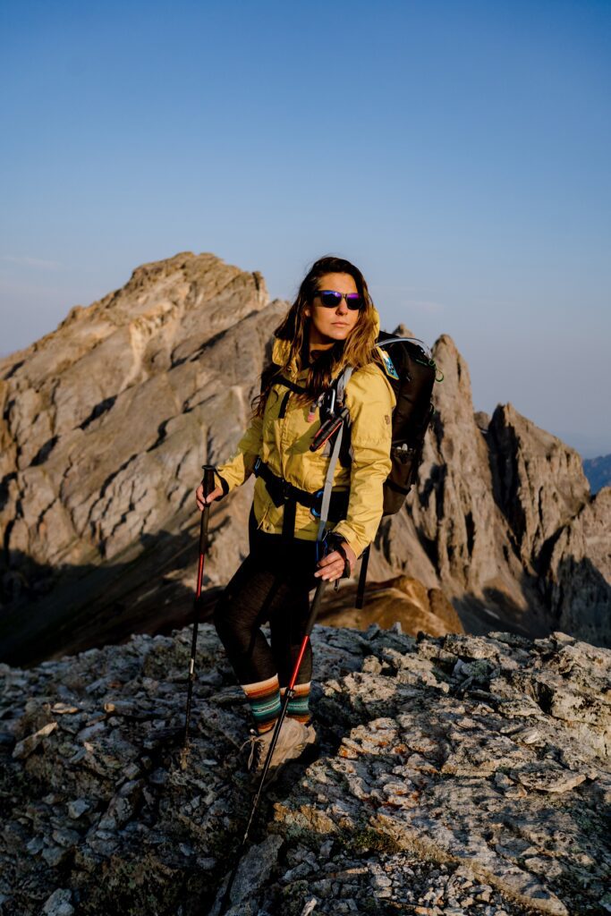 An elopement photographer on the summit of V2 peak in the San Juan mountains of Colorado just after sunrise
