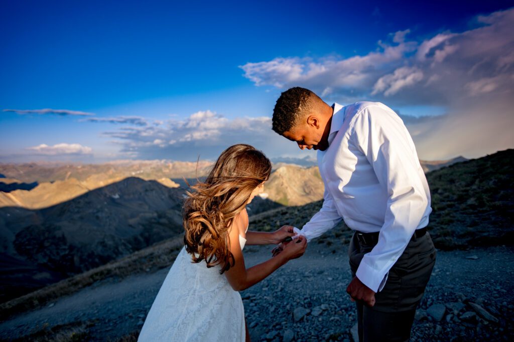 A bride helping a groom get his suit on for their wedding on the top of Handies Peak in southern Colorado
