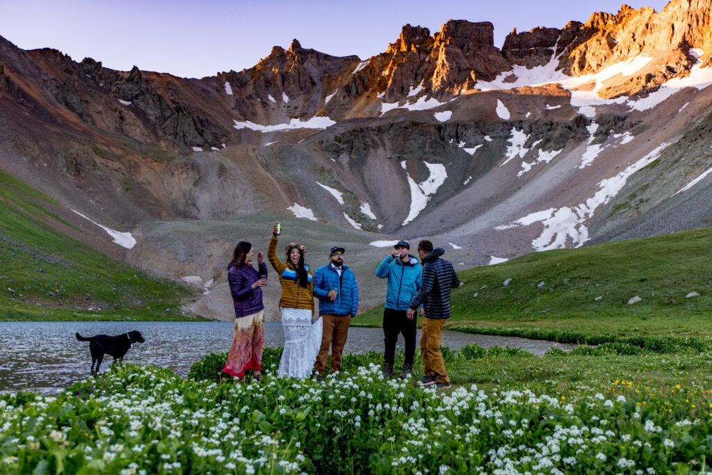 A group celebrating an elopement in a wildflower meadow hiking above Ridgway Colorado