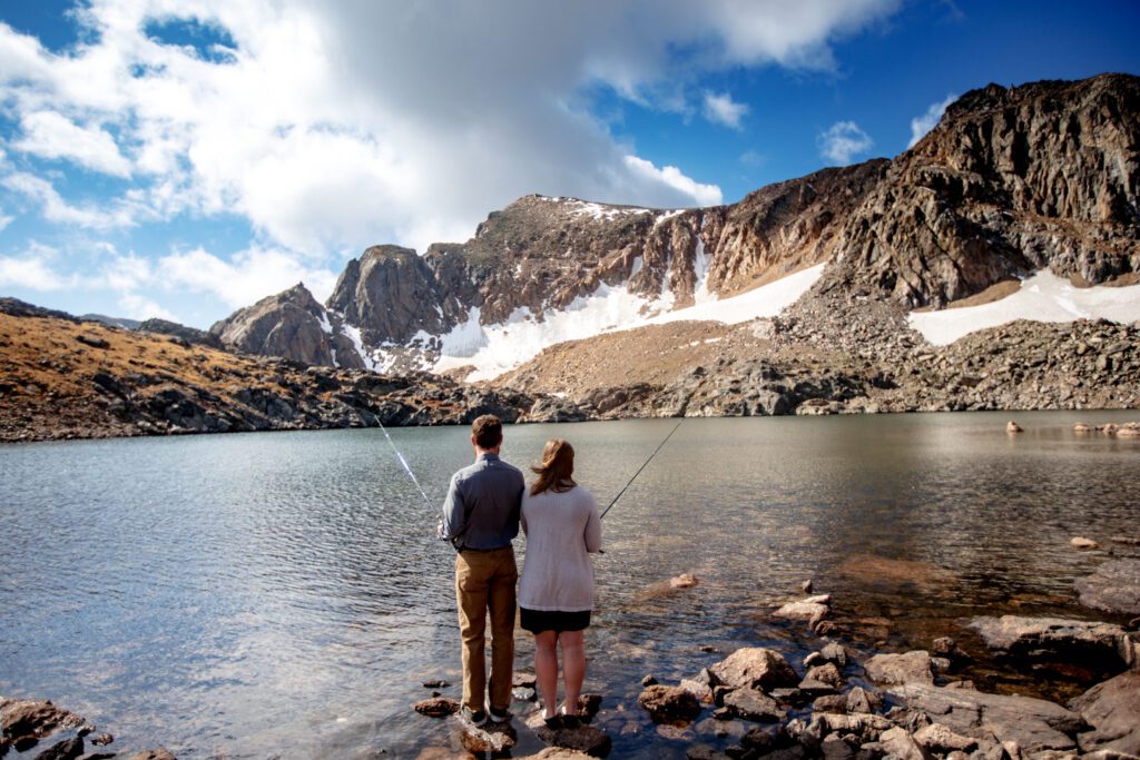 A bride and a groom fishing in an alpine lake near Arapahoe pass in Colorado
