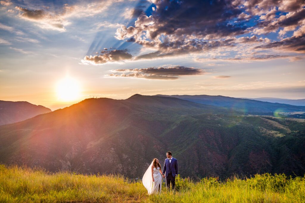 A newly wed couple walking through an alpine field in Glenwood Springs at sunrise