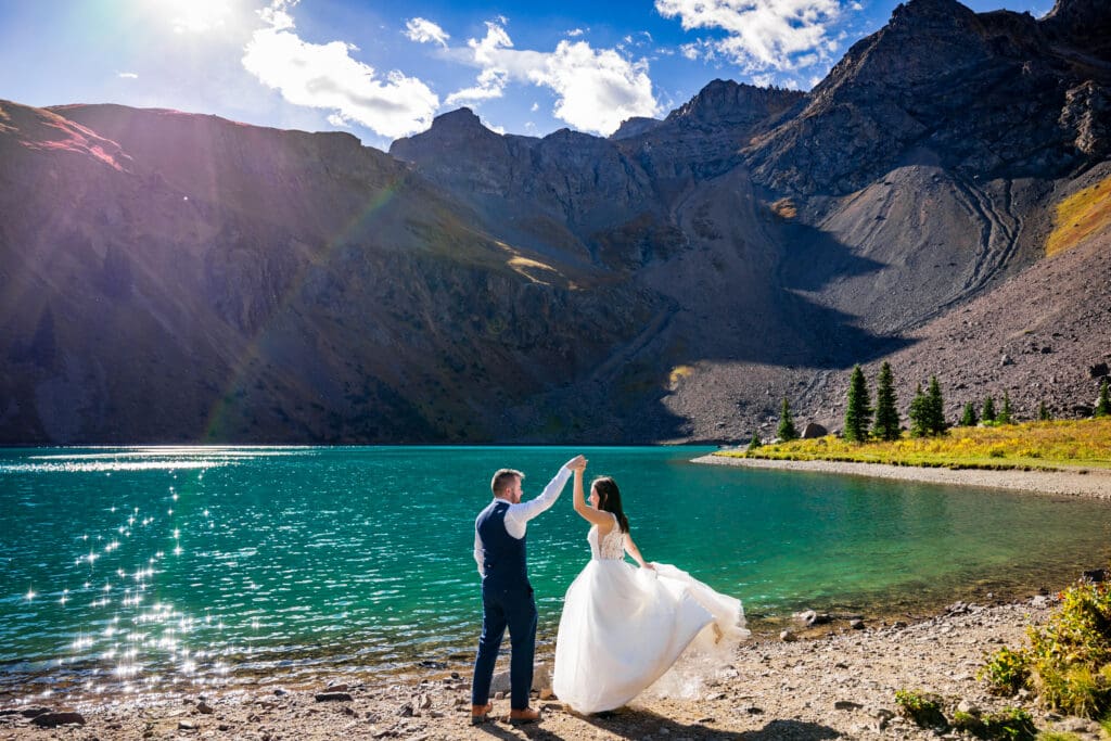 A groom spins his bride as they share their first dance at the shorline of Lower Blue Lakes outside of Ridgway Colorado at their intimate hiking elopement