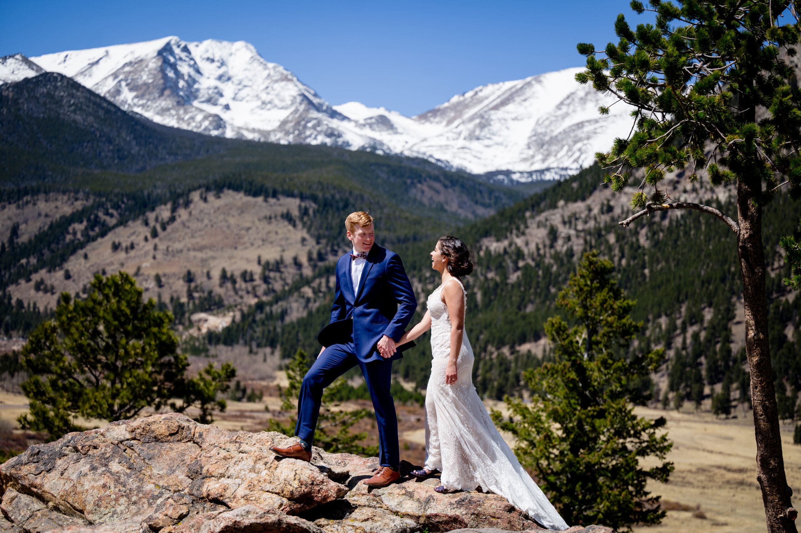 A groom leading his bride on a walk over some rocks in Rocky Mountain National Park for their couple's portraits