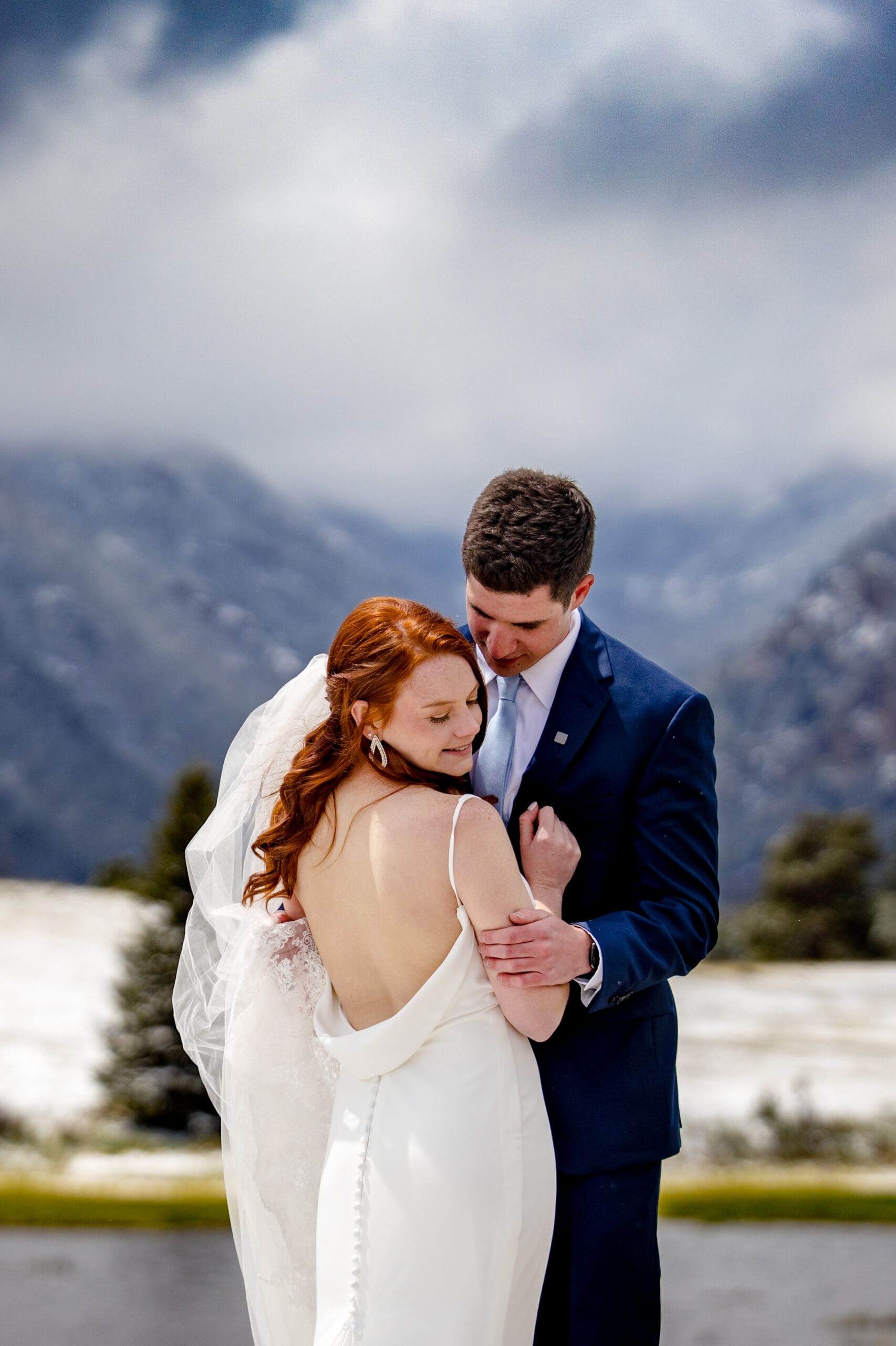 A bride and groom taking spring portraits in Rocky Mountain National Park on a snowy spring day