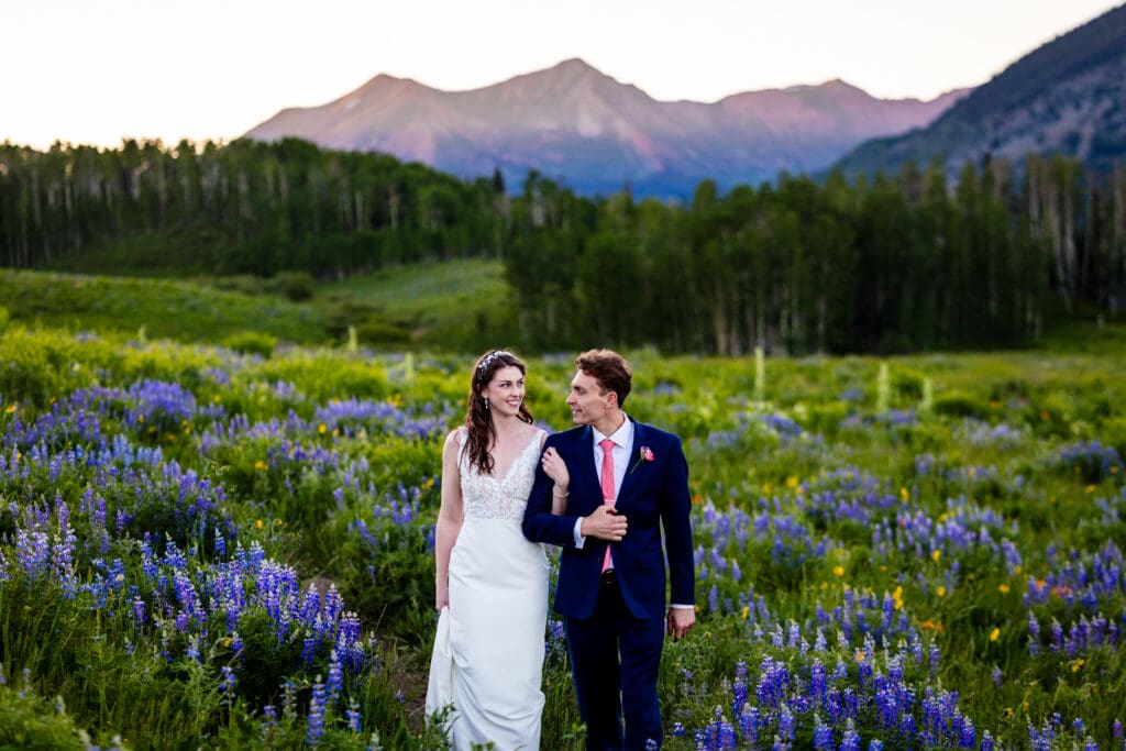 A bride and a groom on Teddy's Trail in Crested Butte during prime Lupine season at sunset on their wedding day